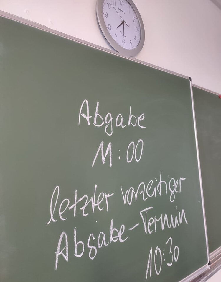 Auf einer Tafel im Klassenraum stehen die Absagetermine zur heutigen schriftlichen Prüfung im Fach Englisch.