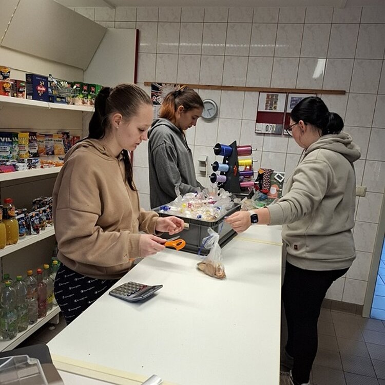 Drei weibliche Auszubildende portionieren die Plätzchen in Tüten und sortieren sie in eine Transportkiste.