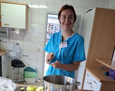 Eine Auszubildende steht in türkiser Schütze in der Lehrküche der Euro-Schulen Hoyerswerda und schneidet die Äpfel für das Apfelmus.