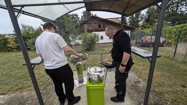 Leibliches Wohl. Zwei Männer grillen im Garten der Euro-Schulen Hoyerswerda mit zwei Kugelgrills Würstchen.