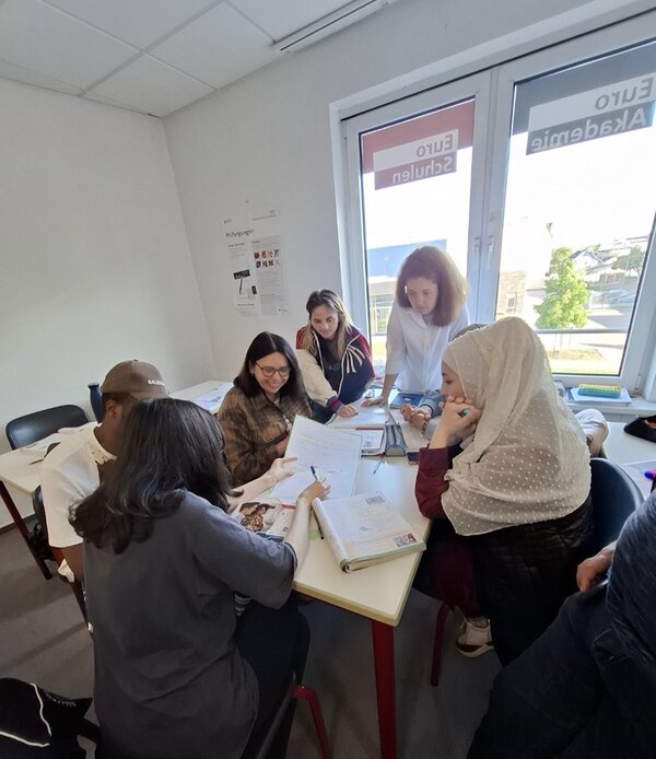 Sechs Teilnehmerinnen des B2-Kurses sitzen an einem Tisch und bearbeiten Aufgaben.