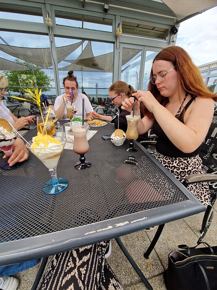Abschlussfeier der Azubis Die Auszubildenden sitzen draußen in einem Eiscafé und genießen ihre großen, bunten Eisbecher.