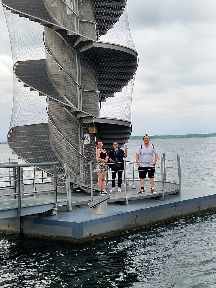 Abschlussfeier der Azubis Die Auszubildenden posieren am Fuße des Pegelturm, der auf der Wasseroberfläche des Goitzschesees schwimmt für ein Gruppenbild.