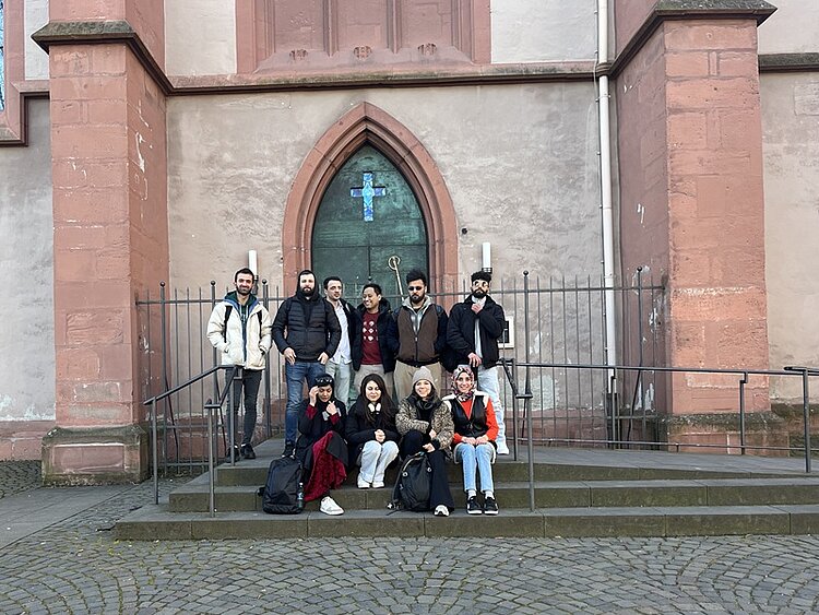 Mainzer Geschichte Teilnehmende des Orientierungskurses posieren vor der St. Stephan Kirche in Mainz für ein Foto.