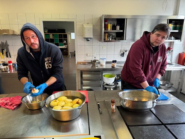 Zwei Teilnehmer stehen in der Küche und waschen und schälen die selbst geernteten Äpfel für die weitere Verarbeitung.