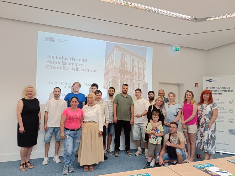 Eine Gruppe des B2-Kurses der Euro-Schulen Zwickau posiert gemeinsam nach der Vorstellung der Industrie- und Handelskammer Chemnitz in einem Seminarraum.