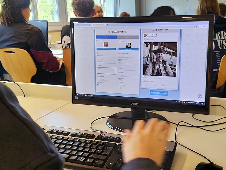 Auf einem Schreibtisch steht eine Computerbildschirm, auf dem die Seite Facebook geöffnet ist.