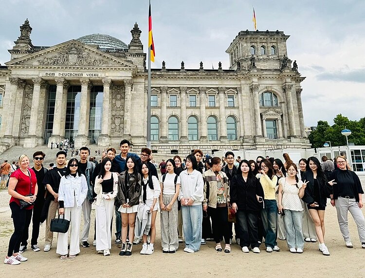Ein unvergesslicher Ausflug nach Berlin Die große Gruppe der Sprachenschülerinnen und -Schüler steht vor dem Reichstagsgebäude mit dem Sitz des Deutschen Bundestages und posiert für ein Gruppenfoto.