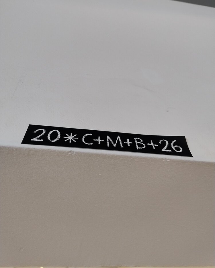 Weiße Wand mit schwarzem Klebestreifen, auf dem in weißer Schrift die traditionelle Sternsinger-Inschrift '20*C+M+B+26' steht. Die Aufnahme entstand anlässlich des Besuchs der Sternensinger am 6. Januar 2026 an den Euro-Schulen und der Euro Akademie Berlin. Die Inschrift symbolisiert den Segen der Sternsinger für das Jahr 2026 und ist gut lesbar mittig auf dem Klebestreifen platziert. Der Hintergrund ist einfarbig und lenkt nicht vom Schriftzug ab.