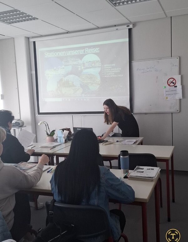 Eine Teilnehmende steht vorn am Whiteboard und trägt ihren Mitteilnehmenden des B2-Sprachkurses ihre Präsentation vor.