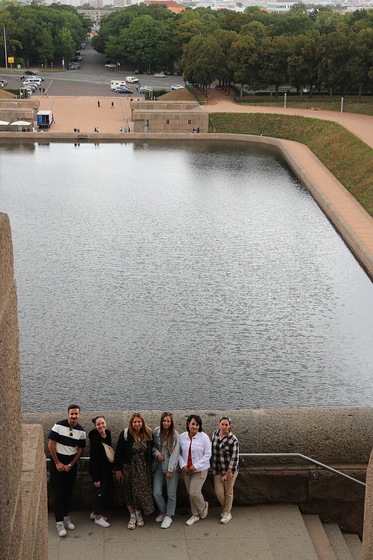 Unser Integrationskurs besucht Leipzig Sieben Personen stehen an einem Geländer mit Blick auf ein Wasserbecken beim Völkerschlachtdenkmal.