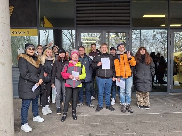 Gruppenbild aller gutgelaunten Teilnehmenden vor dem Messegebäude in Dresden.