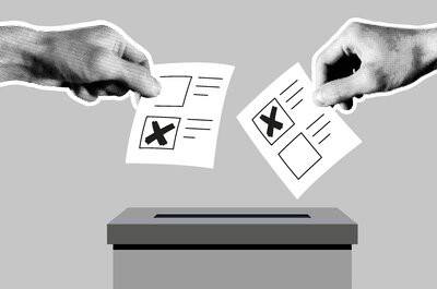  Auf der Grafik, die komplett in grau gehalten ist, ist eine Wahlurne gezeichnet. Zwei fotografierte Hände halten symbolisch Stimmzettel in der Hand, auf denen jeweils ein Kreuz in einem Kästchen ist. Die Hände bewegen die Zettel in Richtung der Öffnung der Wahlurne.