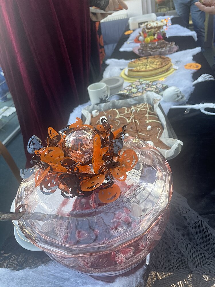 Lange gedeckte Halloween-Tafel mit allerlei Köstlichkeiten in schauriger Ausführung.