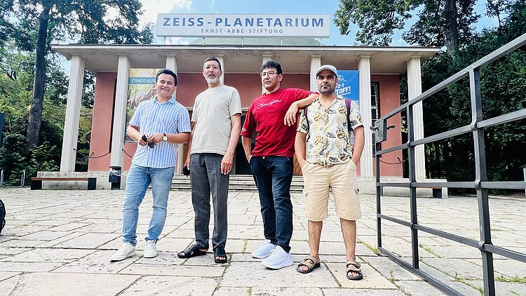 Besuch des Planetariums in Jena und des Landtags in Erfurt Schülerinnen und Schüler der Euro-Schulen Erfurt stehen vor dem Planetarium für ein Gruppenfoto. Das Planetarium hat am Eingang sieben römische Säulen und die Fassade ist hautfarben gestrichen.