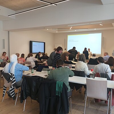 Viele Leute sitzen an einem Konferenztisch und halten eine Besprechung ab.