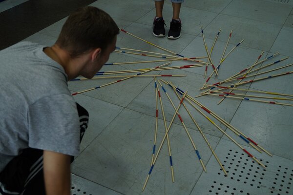 Geschicklichkeit und Ruhe. Beim Mikado versucht ein Teilnehmer im grauen Shirt sich zu fokussieren und den richtigen Stab zu ziehen.