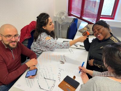 Ein Mann und drei Frauen gestalten gemeinsam ein Plakat.