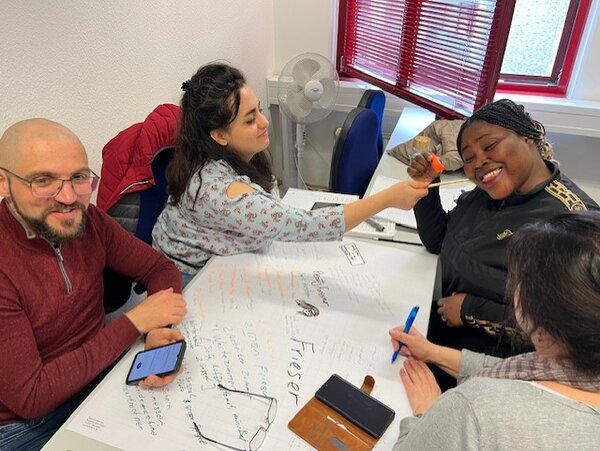 Ein Mann und drei Frauen gestalten gemeinsam ein Plakat.