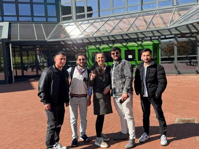 Fünf Teilnehmende des HSA-Kurses der Euro-Schulen Düren stehen gemeinsam vor dem Eingangsbereich einer Schule und lächeln in die Kamera.