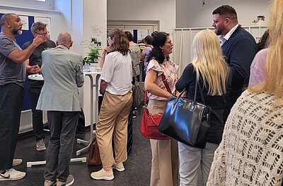 10 Jahre Reinickendorfer Ausbildungsdialog Die Teilnehmenden des Reinickendorfer Ausbildungsdialogs tauschen sich rege aus, an Stehtischen.