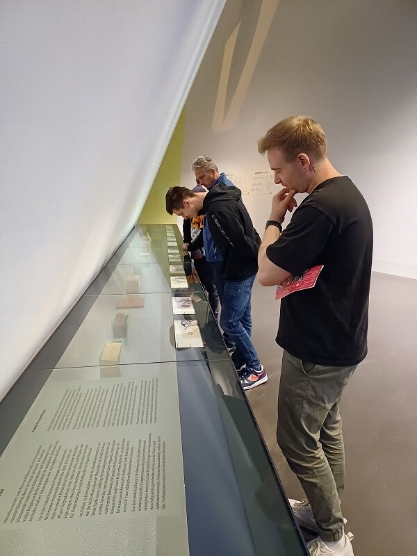 Die Teilnehmenden stehen vor Glasvirtrinen und schauen sich interessiert die militärischen Ausstellungsstücke des Museums an. 