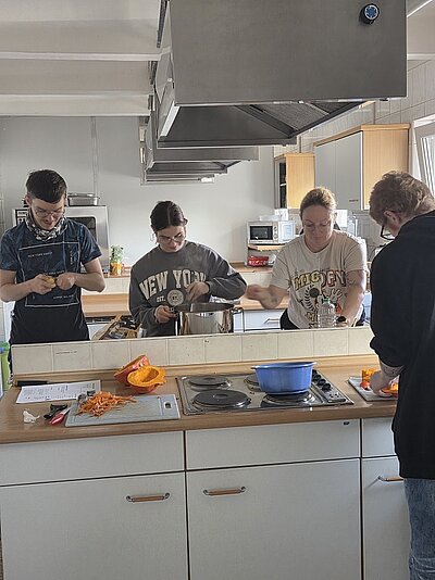 Herbstliche Köstlichkeit Vier Schüler*innen bereiten in der Schulküche die Suppe vor: Sie schnippeln Kürbis, schälen Karotten, Zwiebeln und Knoblauch und rühren die Brühe an.