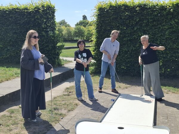 Mitarbeitende der Euro-Schulen stehen mit ihren Teams auf dem Minigolf-Platz und schauen beraten sich.