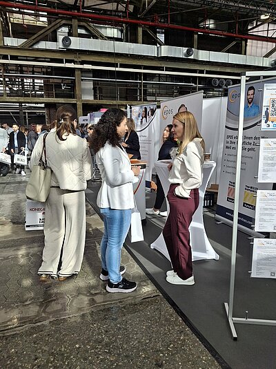 Zwei Frauen unterhalten sich angeregt an einem Messestand.