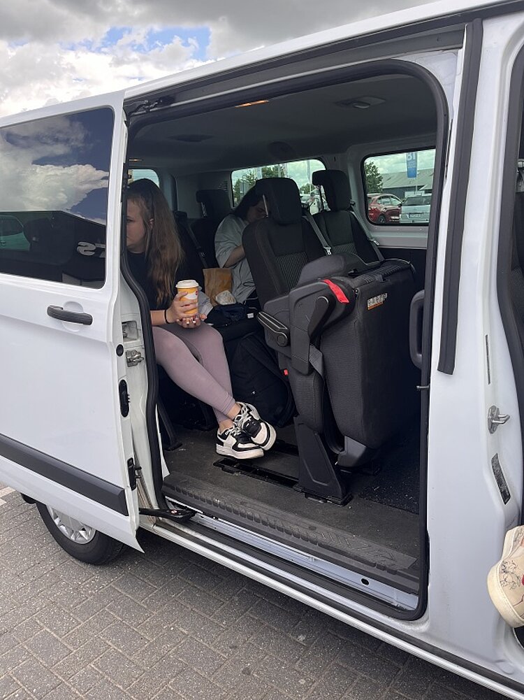 Abschlussfahrt der VK21 an die Ostsee Auf dem Bild ist ein Minibus mit offener Schiebetür zu sehen, wo die Schüler drinsitzen.