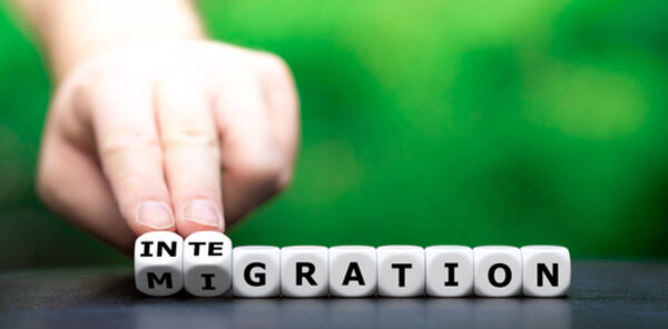 Eine Hand dreht Würfel um und verändert damit das Wort Migration in Integration. 