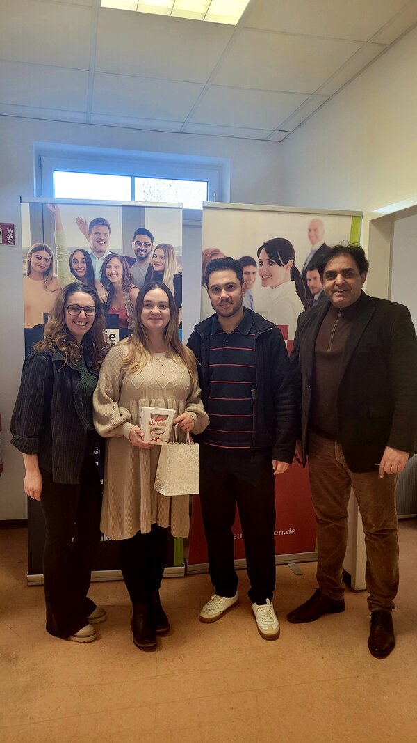 Vier Personen stehen vor Roll-Ups der Euro Akademie, eine Frau in der Mitte hält eine Raffaello-Packung und eine kleine Geschenktüte, alle schauen freundlich in die Kamera.