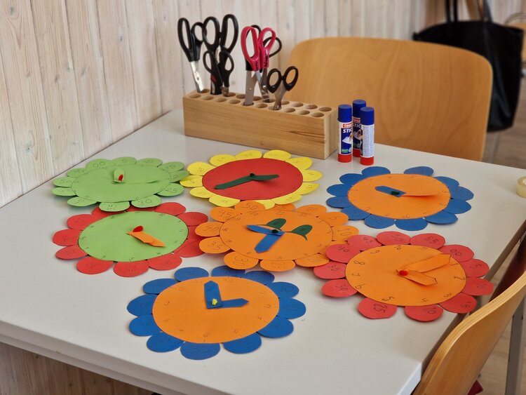 Auf einem Tisch liegen bunte Uhren aus.