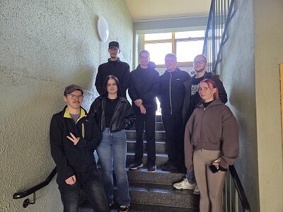 Eine Gruppe junger Teilnehmender steht gemeinsam auf einer Treppe und posiert für ein Gruppenfoto.