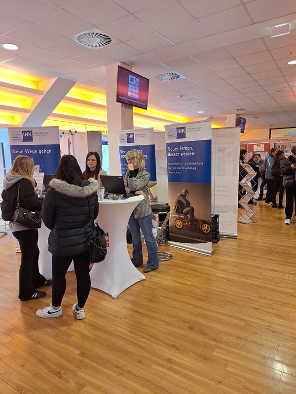 Zwei Teilnehmerinnen stehen am Messestand der IHK und informieren sich.