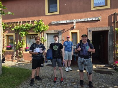 Die vier männlichen Auszubildenden zu Fachlageristen posieren nach erfolgreicher Pilgerwanderung gut gelaunt vor dem Wal- und Wüstenberghaus.
