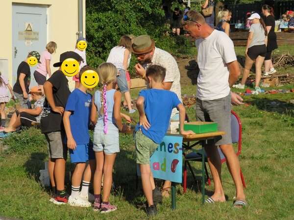 Interessierte Kinder und Erwachsene stehen vor einer Mitmach-Station zum Sinne erforschen.