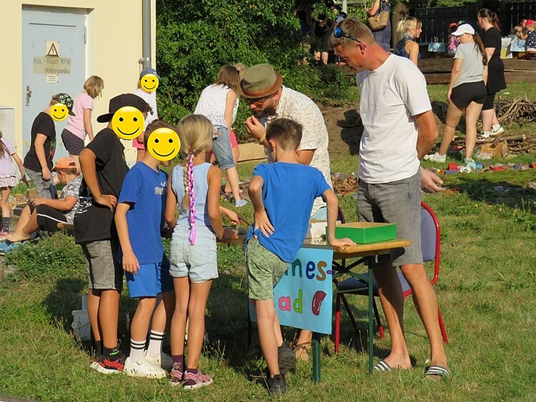 Der nächste Schritt unserer Klimaschule Interessierte Kinder und Erwachsene stehen vor einer Mitmach-Station zum Sinne erforschen.