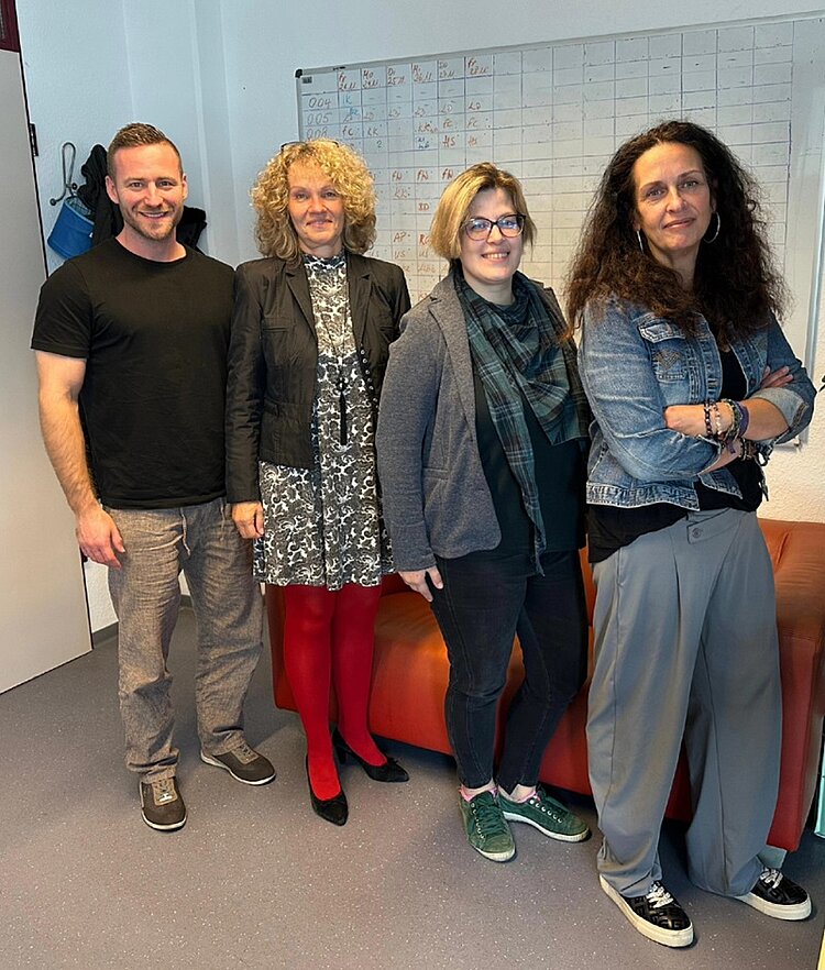 Gruppenfoto mit zwei Mitarbeitenden der Arbeitsagentur sowie der Leitung der Euro-Schulen und einer weiteren Mitarbeiterin. Die vier Personen stehen lächelnd in einem Büro vor einem Whiteboard und posieren gemeinsam für das Foto anlässlich eines Austauschs zwischen Arbeitsagentur und Euro-Schulen zur Maßnahme Bali.