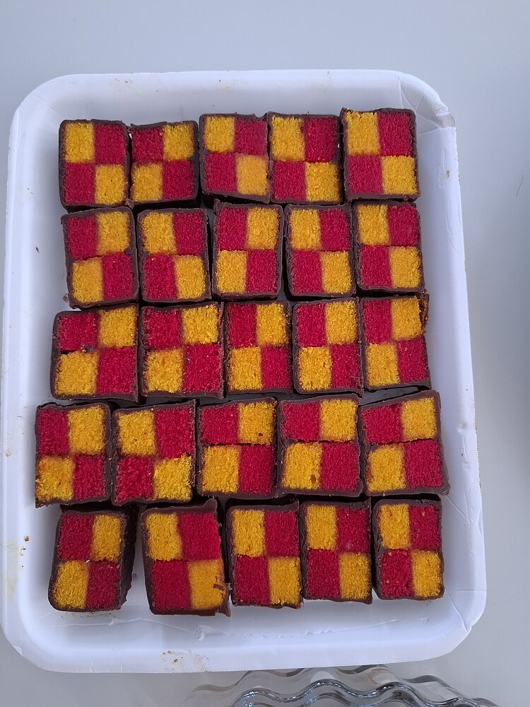 Sternstunde im Leben eines Deutschlehrers Ein Tablett mit kleinen Kuchenstücken im Schachbrettmuster, rot und gelb gefärbt und von Schokolade umhüllt.