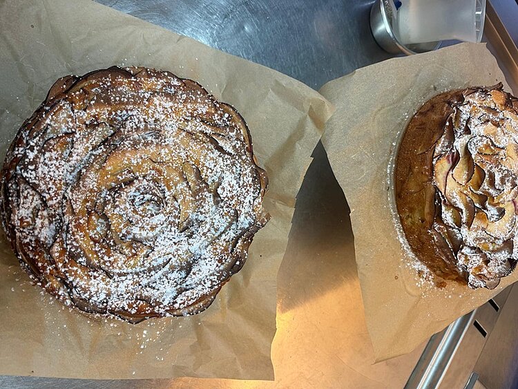 Zwei selbst gebackene Apfelkuchen, die mit Puderzucker betreut sind. 