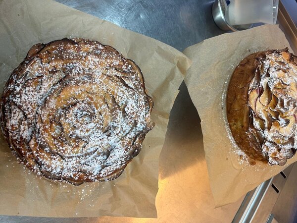 Zwei selbst gebackene Apfelkuchen, die mit Puderzucker betreut sind. 