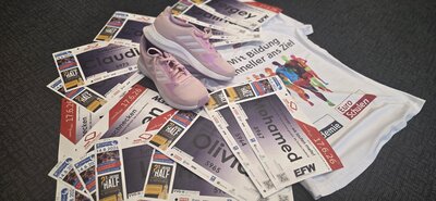 Laufunterlagen mit Startnummern, pinke Sportschuhe und ein Euro-Schulen-Laufshirt liegen auf dem Boden und bereiten auf eine Sportveranstaltung vor.