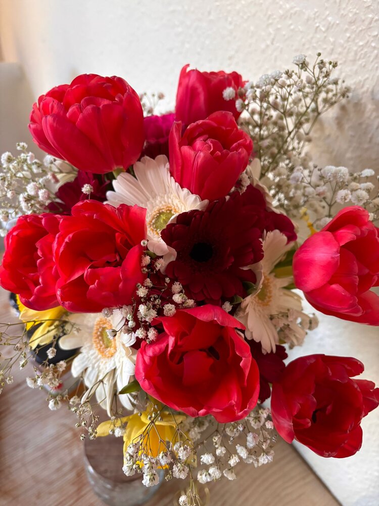 Ein Blumenstrauß aus roten Tulpen, weißen Gerbera und Schleierkraut.