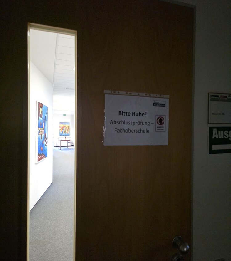 An der Tür zum Klassenraum der Euro Akademie Dresden steht ein Zettel mit dem Hinweis "Bitte Ruhe!" Abschlussprüfung der Fachoberschule.