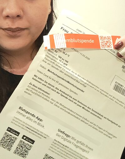 Frau Sabine Fuchs der Euro-Schulen Aschaffenburg hält eine Bescheinigung zur Blutspende in die Kamera.