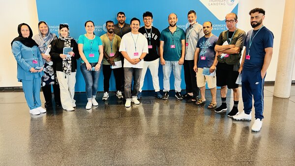 Zu sehen sind Schülerinnen und Schüler der Euro-Schulen Erfurt, die mit Politikerinnen und Politiker des Landtags vor einer blauen Wand für ein Gruppenfoto stehen.