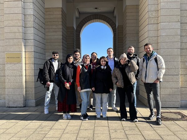 Teilnehmende des Orientierungskurses posieren vor der St. Stephan Kirche in Mainz für ein Foto.