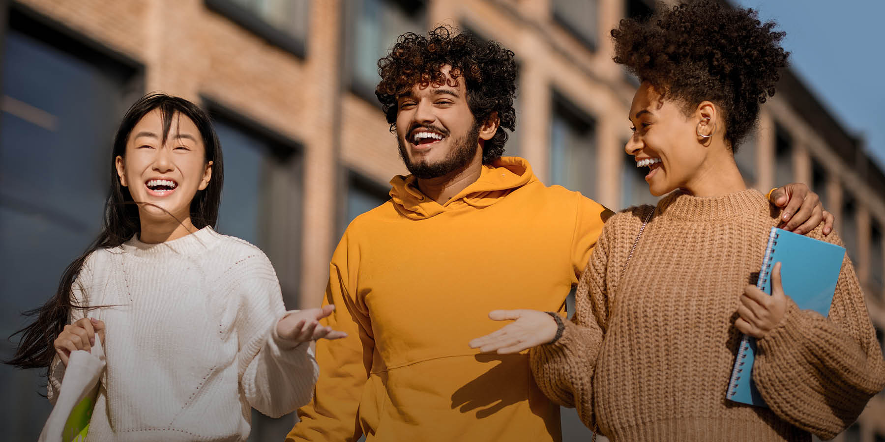 Drei junge Menschen laufen nebeneinander und unterhalten sich lachend.